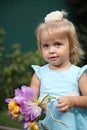 Sweet smiling little girl with long blond hair, sitting on grass in summer park, closeup outdoor portrait. Royalty Free Stock Photo